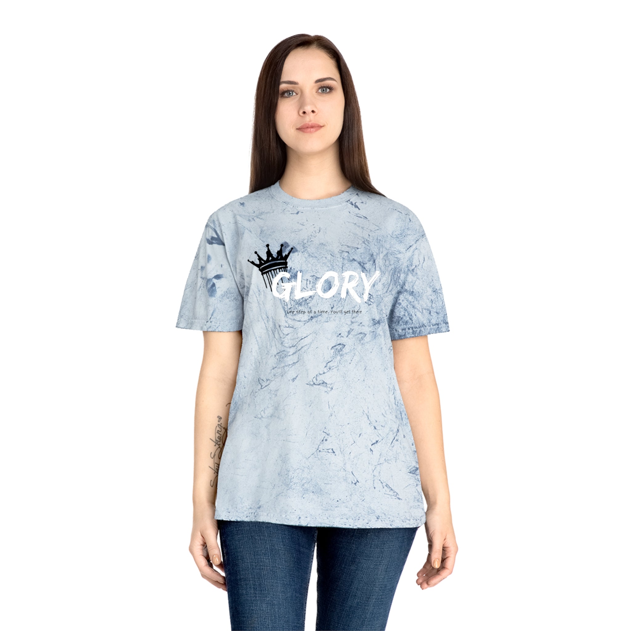Person wearing a light blue tie-dye t-shirt with 'GLORY' printed on it against a white background