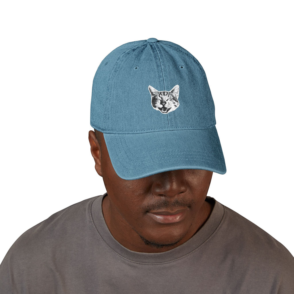 Man wearing a blue cap with a cat face design on a white background