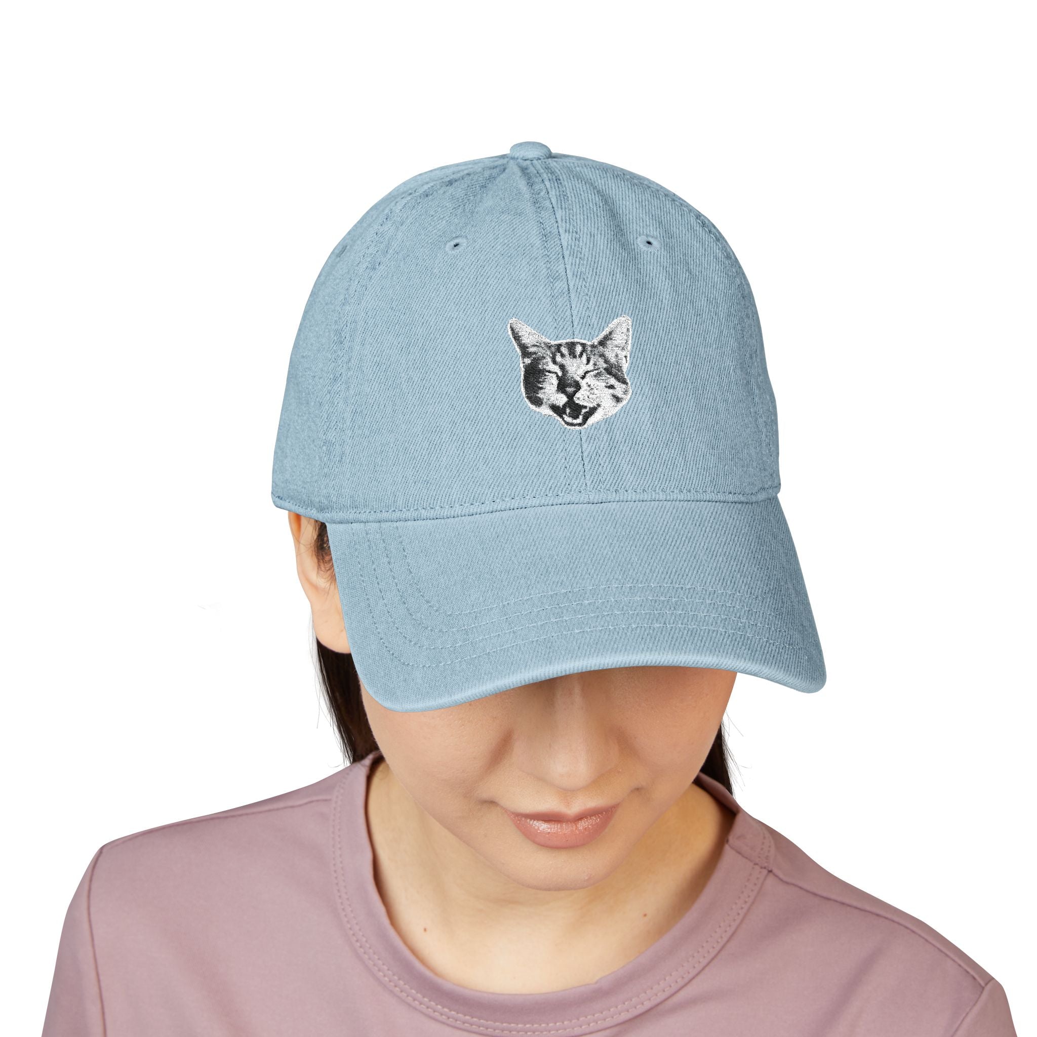 Light blue baseball cap with a cat face design worn by a person on a white background