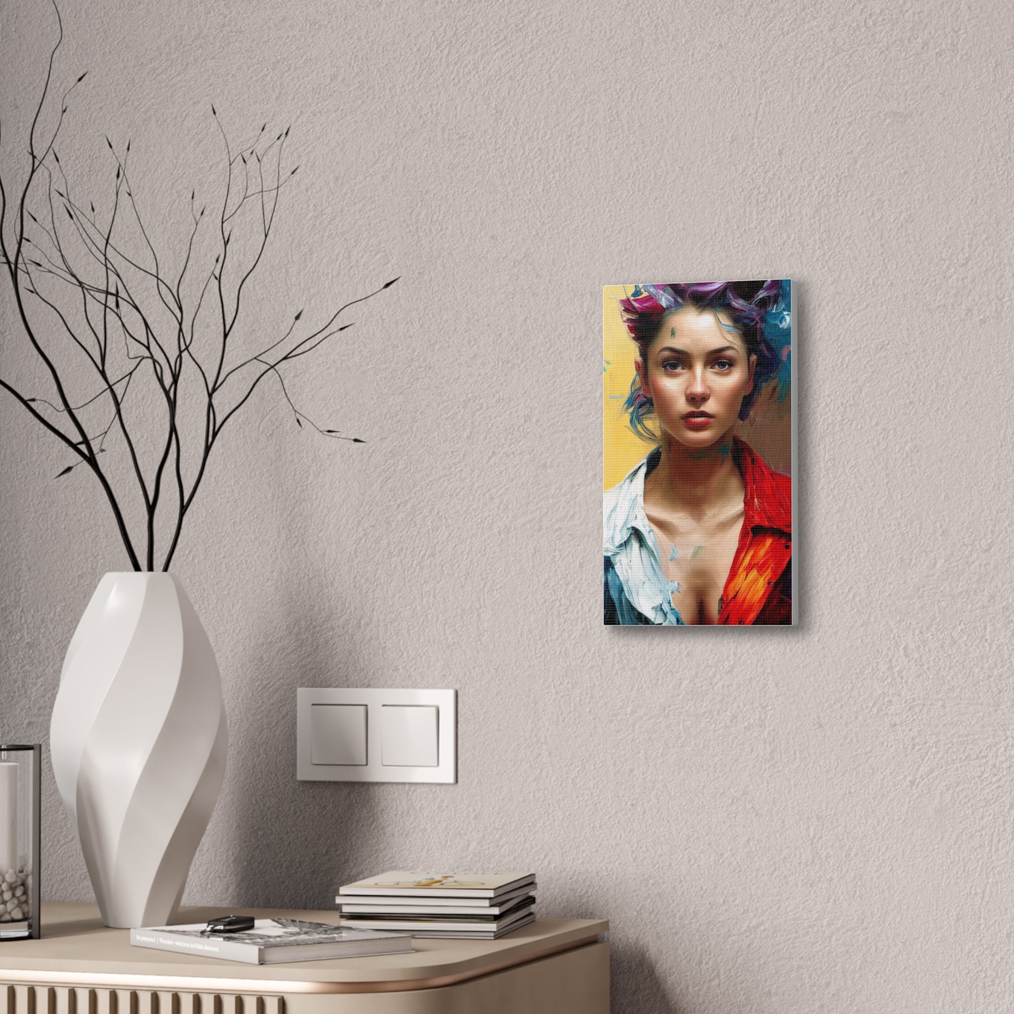 Canvas print of a colorful portrait on a wall next to a vase with branches and books.