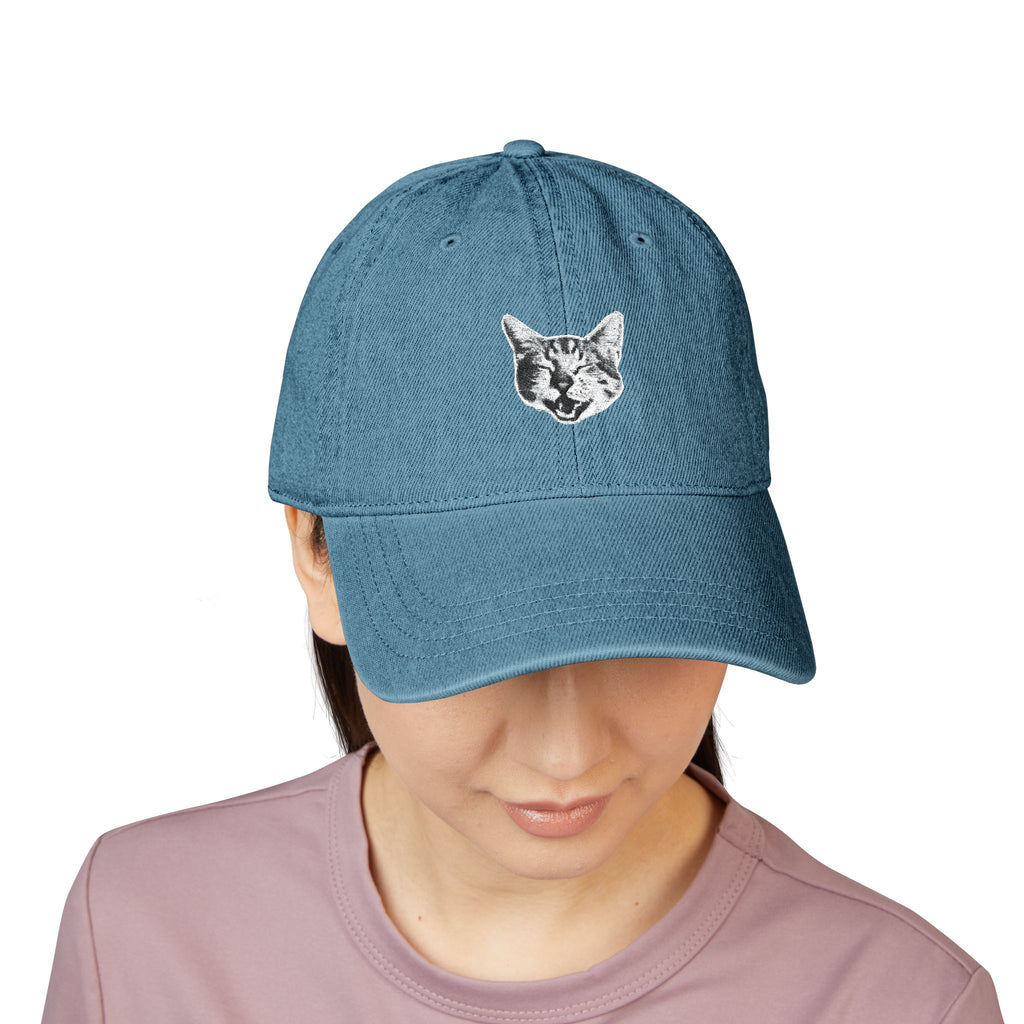 Blue cap with a cat face design worn by a person on a white background