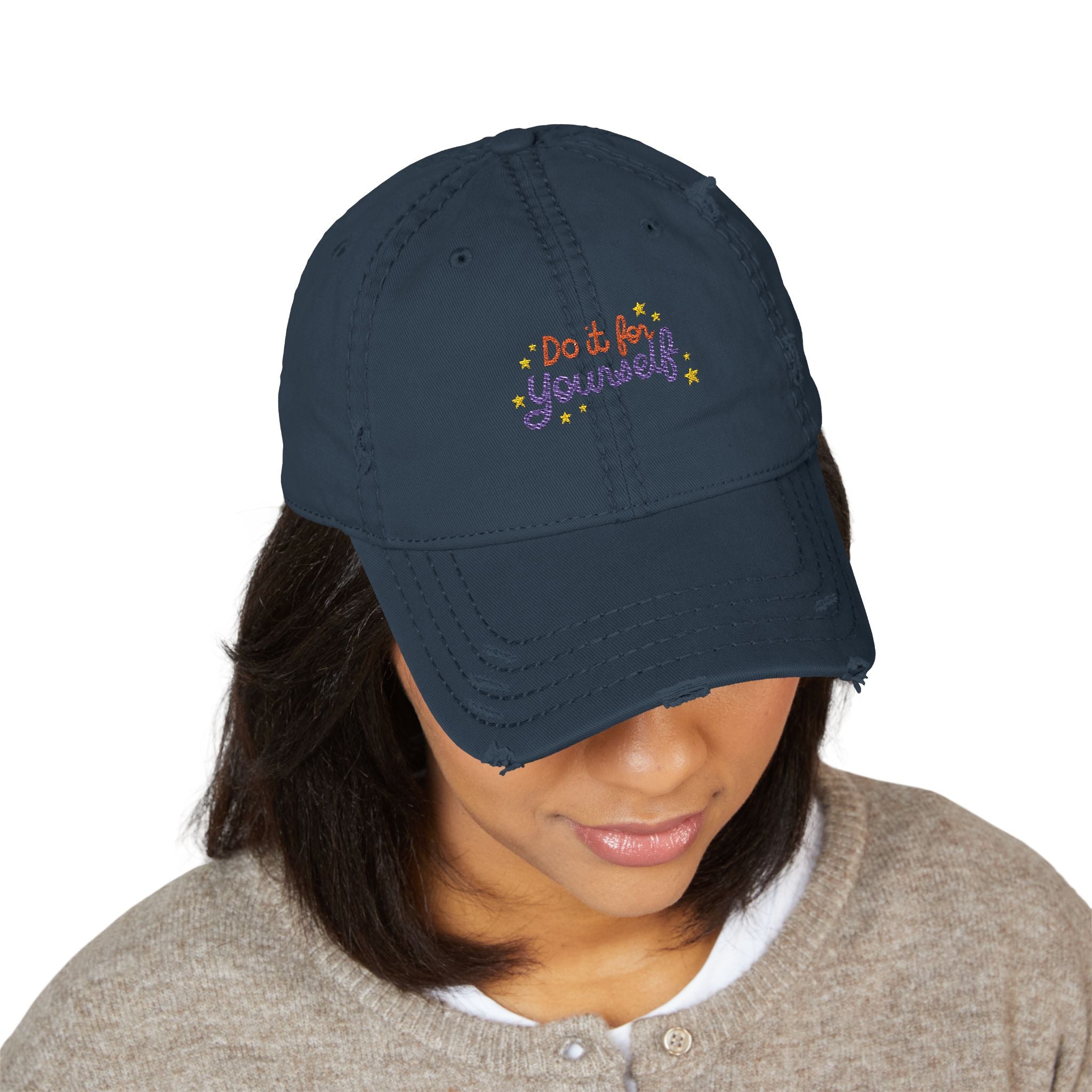 Navy blue cap with 'Do it Yourself' text worn by a person on a white background