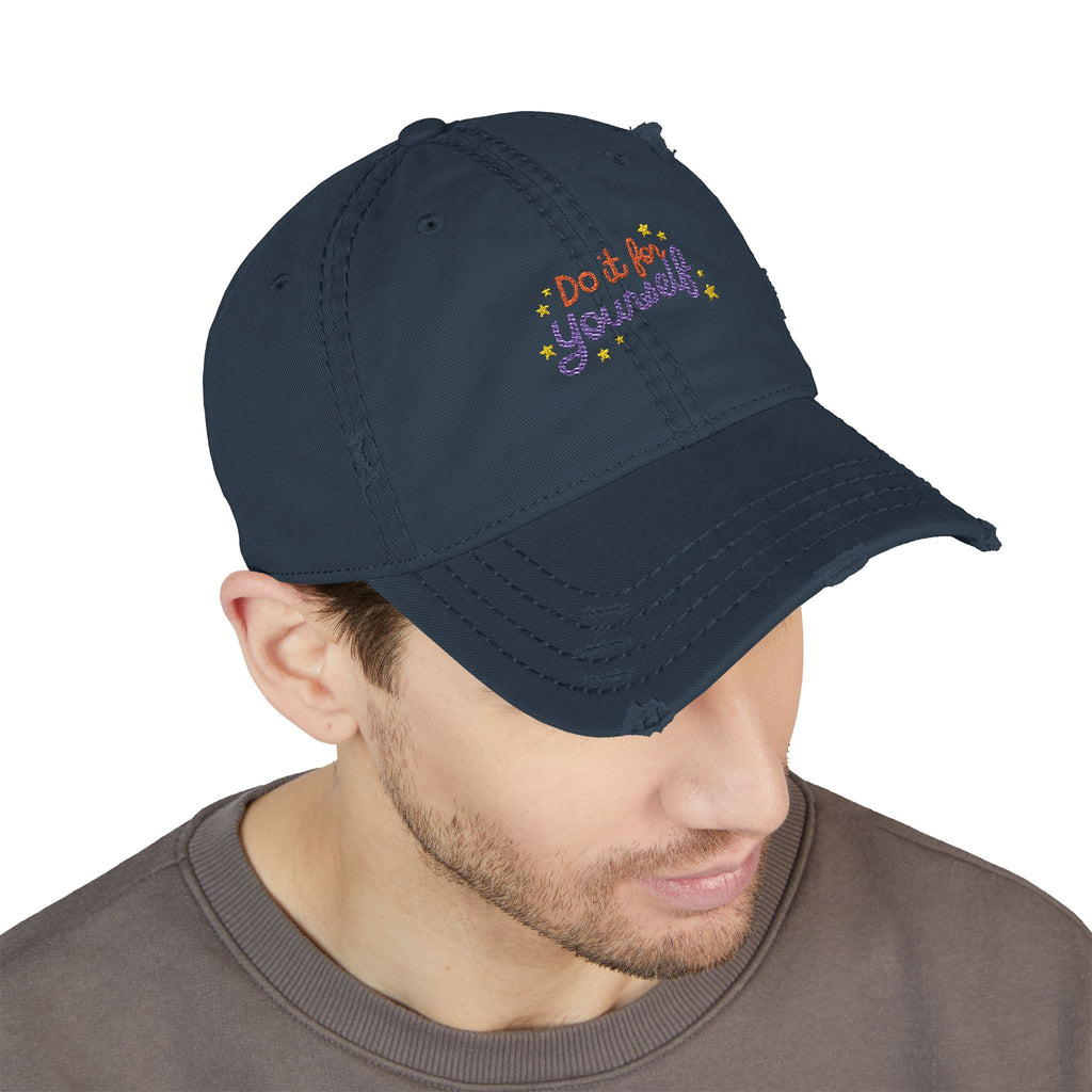 Navy blue cap with 'Do it Yourself' embroidery worn by a person on a white background