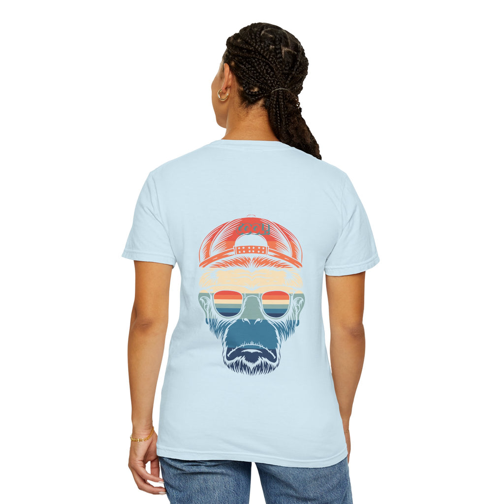 Person wearing a light blue t-shirt with a graphic of a bearded face wearing sunglasses and a cap on the back.