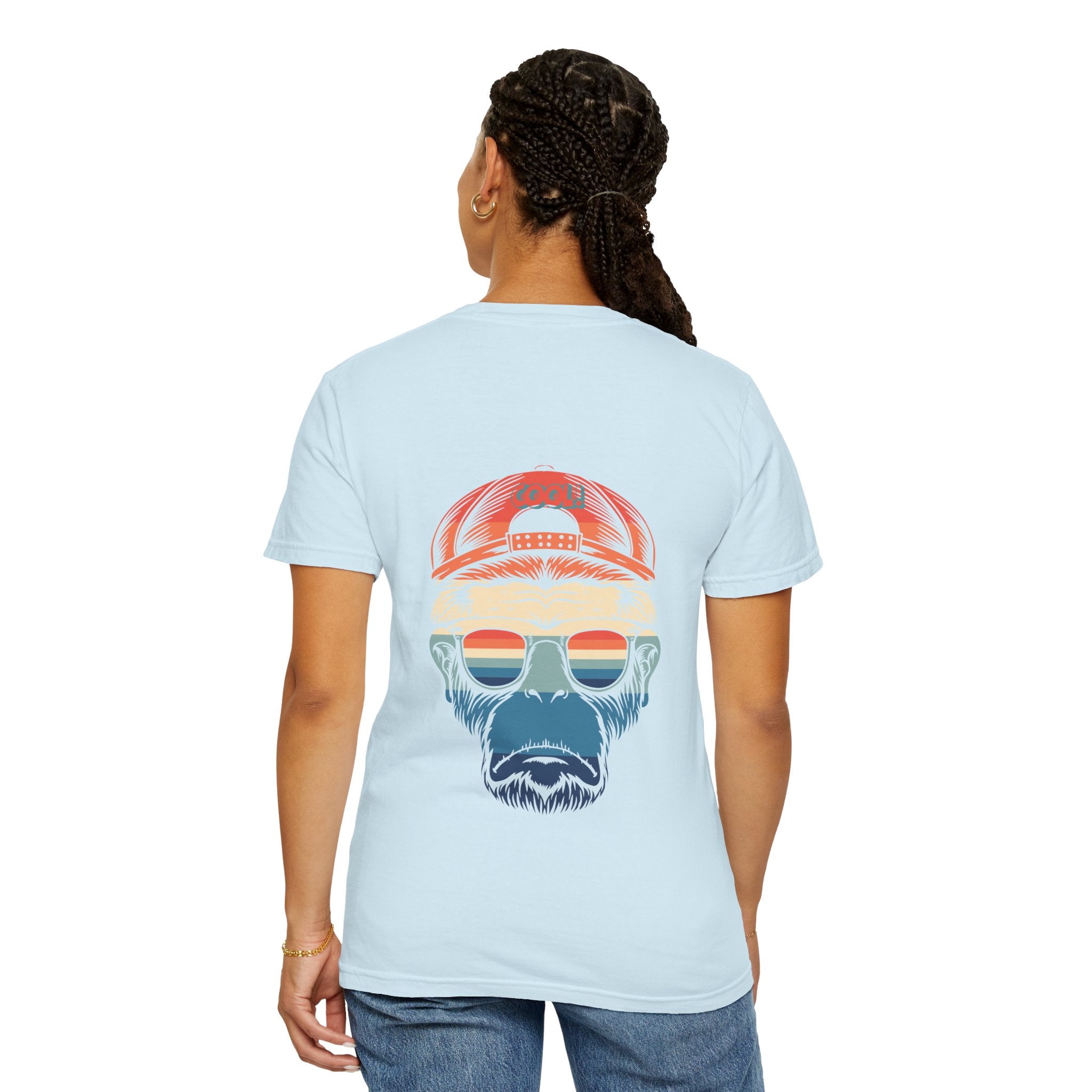 Person wearing a light blue t-shirt with a graphic of a bearded face wearing sunglasses and a cap on the back.