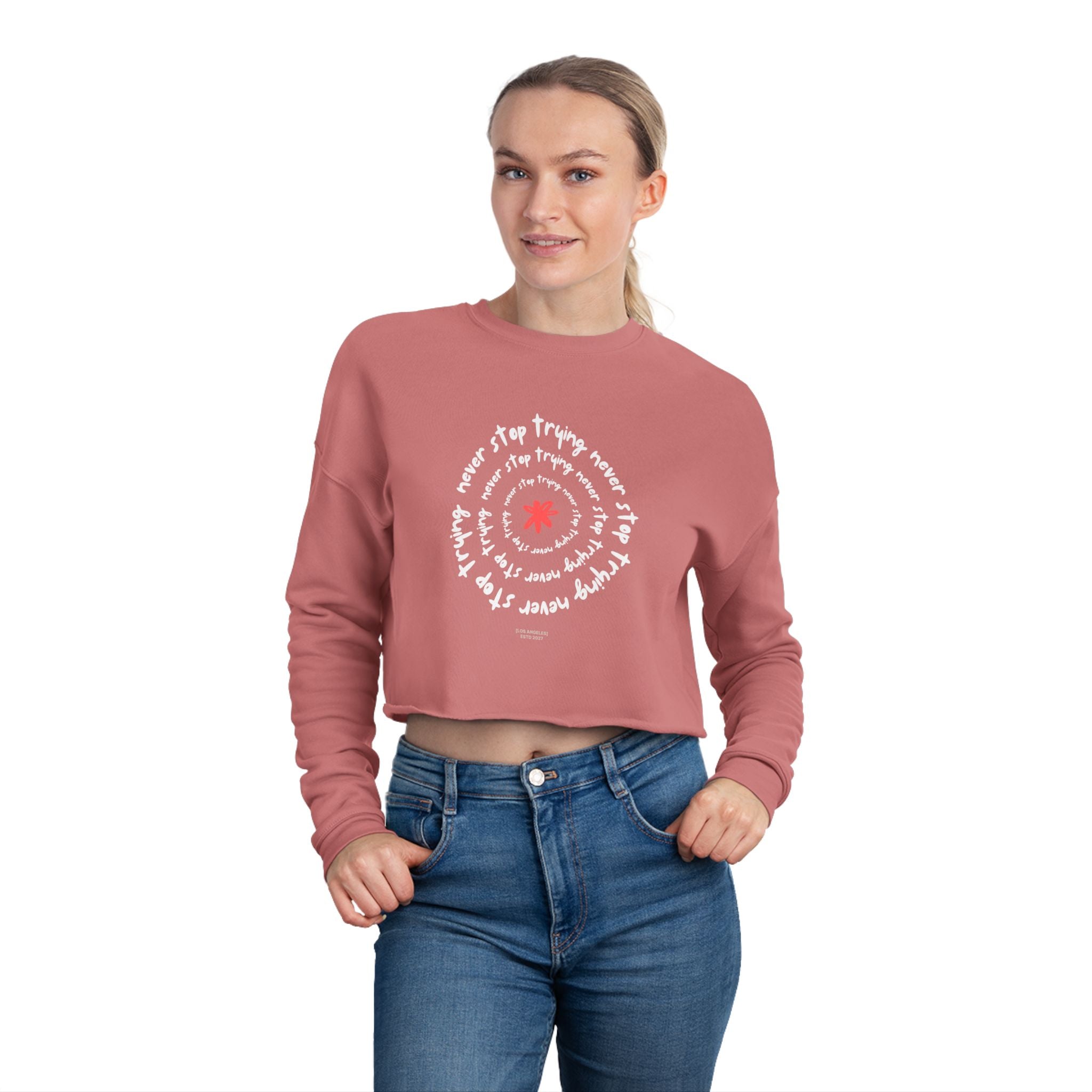 Person wearing a pink cropped sweatshirt with white text and a red heart design on a white background