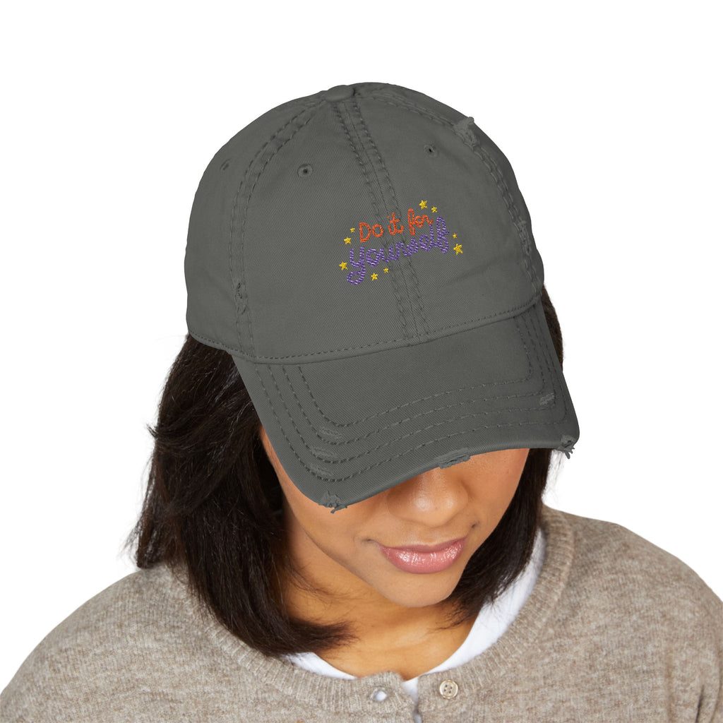 Person wearing a gray cap with colorful text and star designs on a white background