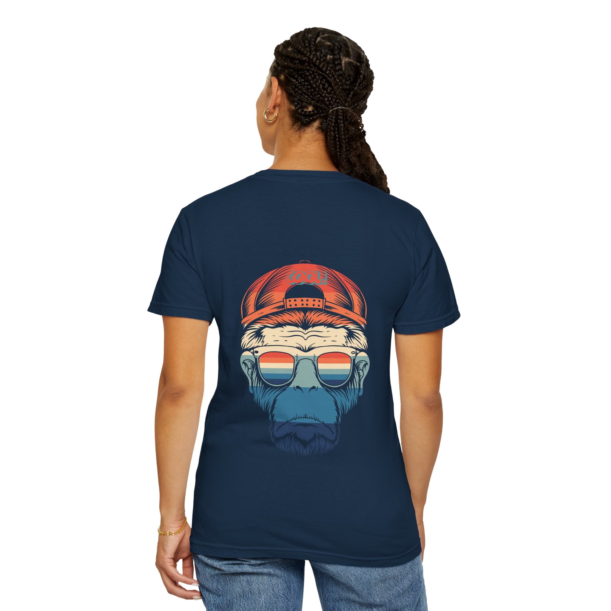 Person wearing a navy blue t-shirt with a graphic design on the back, featuring a face with sunglasses and a cap.