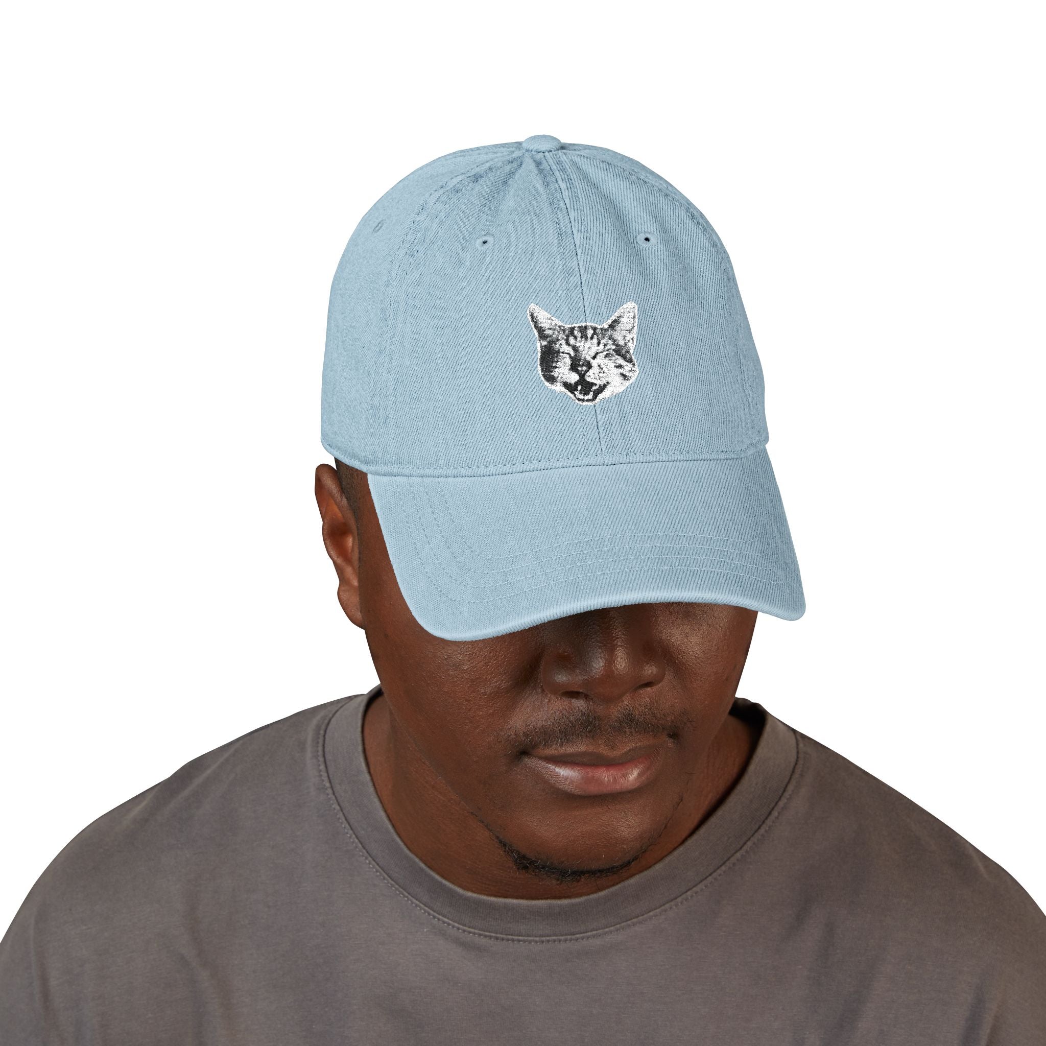 Man wearing a light blue cap with a cat face design on a white background