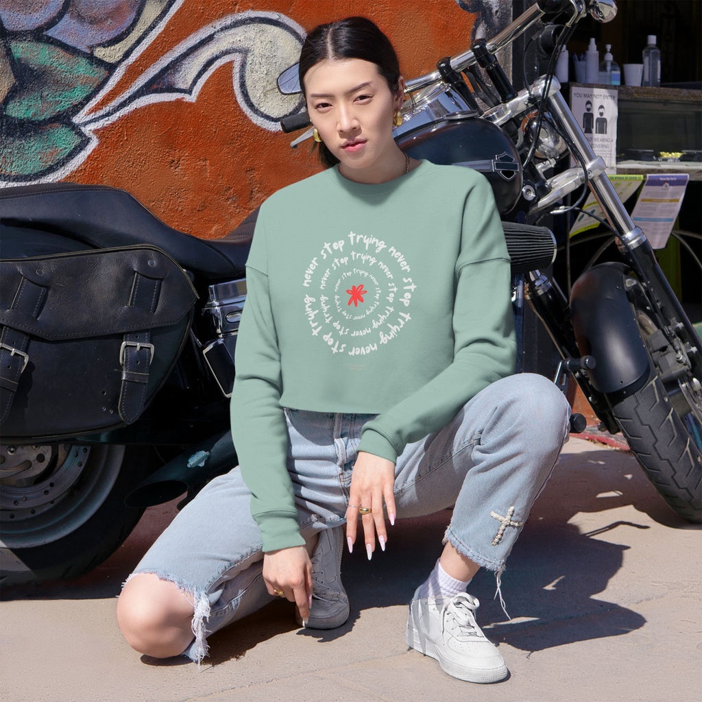 Person wearing a green sweatshirt with text and graphics, sitting in front of a motorcycle.