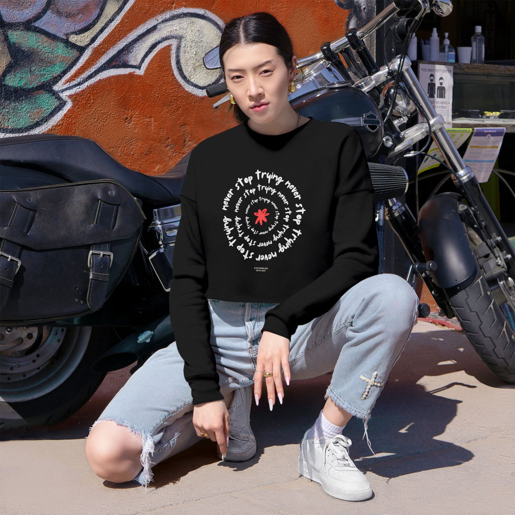 Person wearing a black sweatshirt with white text and design, sitting in front of a motorcycle.