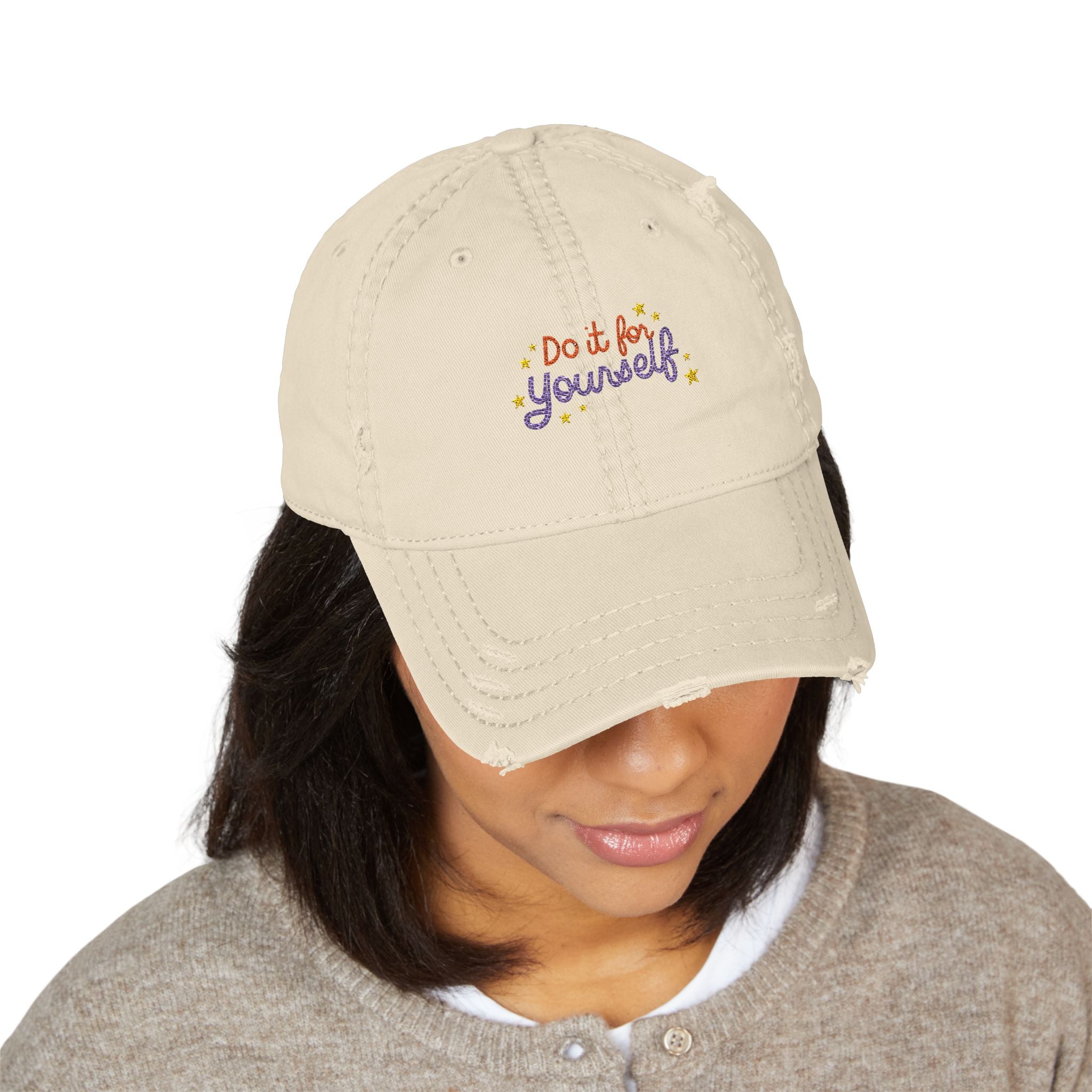 Beige cap with 'Do it for yourself' text worn by a person on a white background